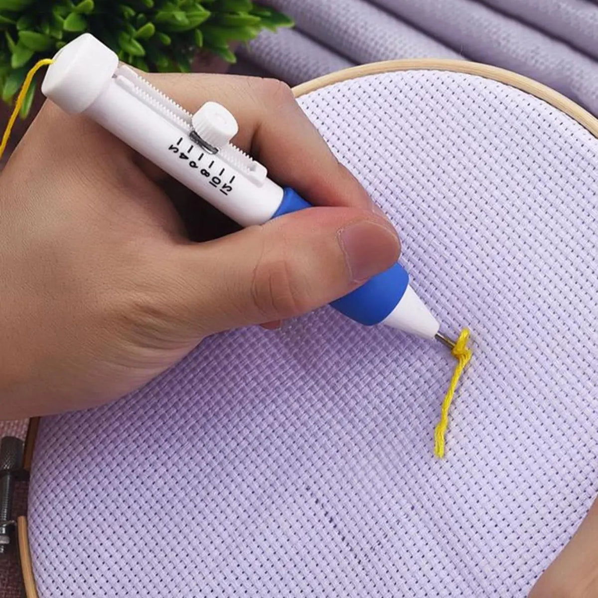 Hand stitching yellow thread into fabric with the punch needle embroidery pen